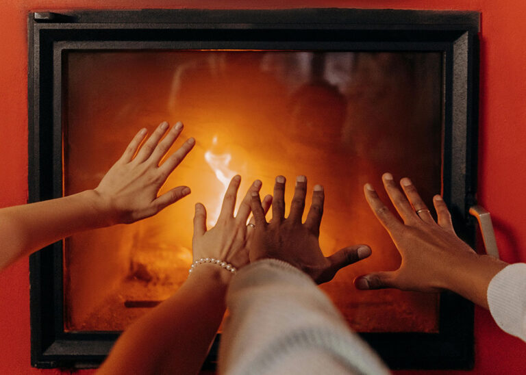 couple's hands in front of warm furnace